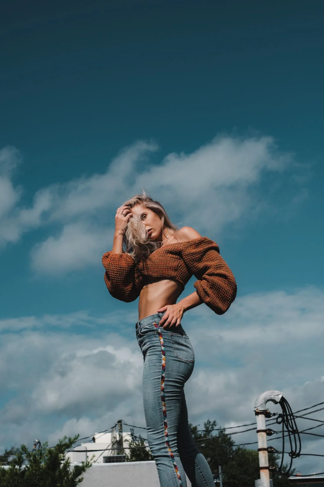 Woman wearing a brown sweater and denim jeans outdoors