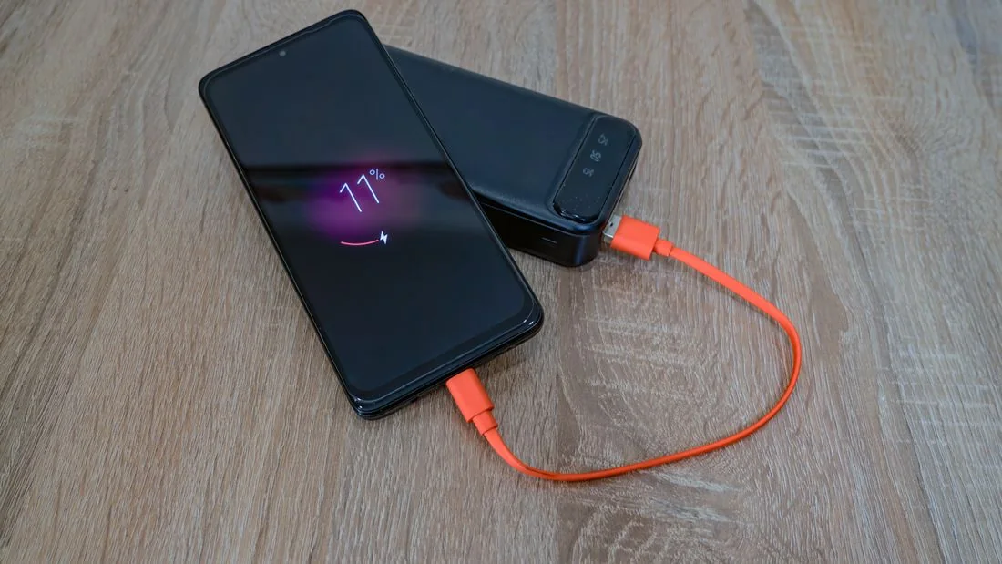 Smartphone connected to a portable power bank with an orange cable